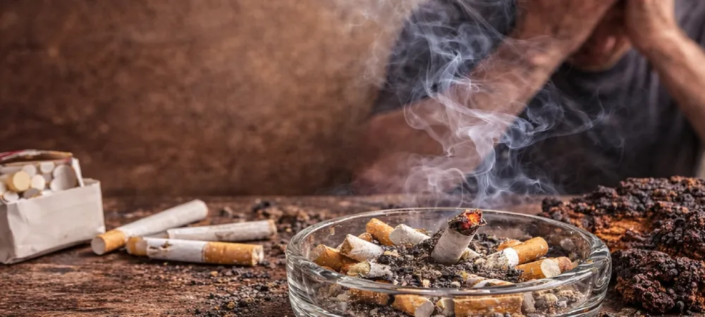 adiccion al tabaco con cenicero lleno de colillas y persona con ansiedad
